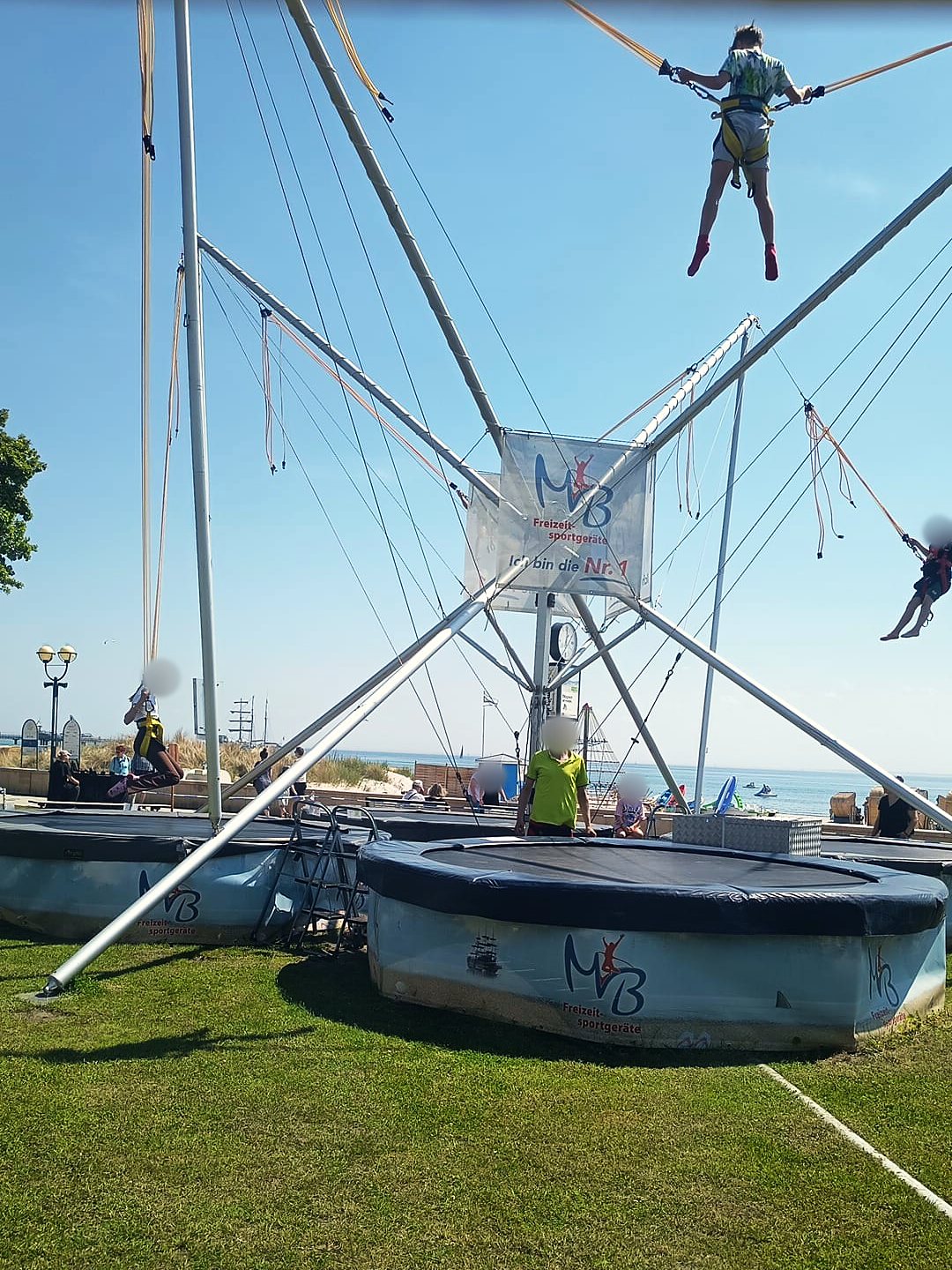 Kinder springen am Bungee-Trampolin an der Grömitzer Kurpromenade, im Hintergrund die Ostsee